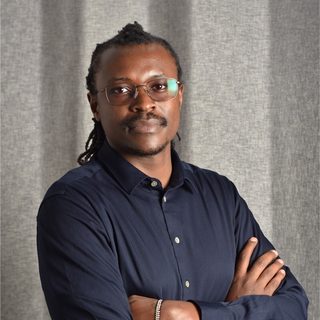 Collins Rotich, in a navy shirt with arms crossed
